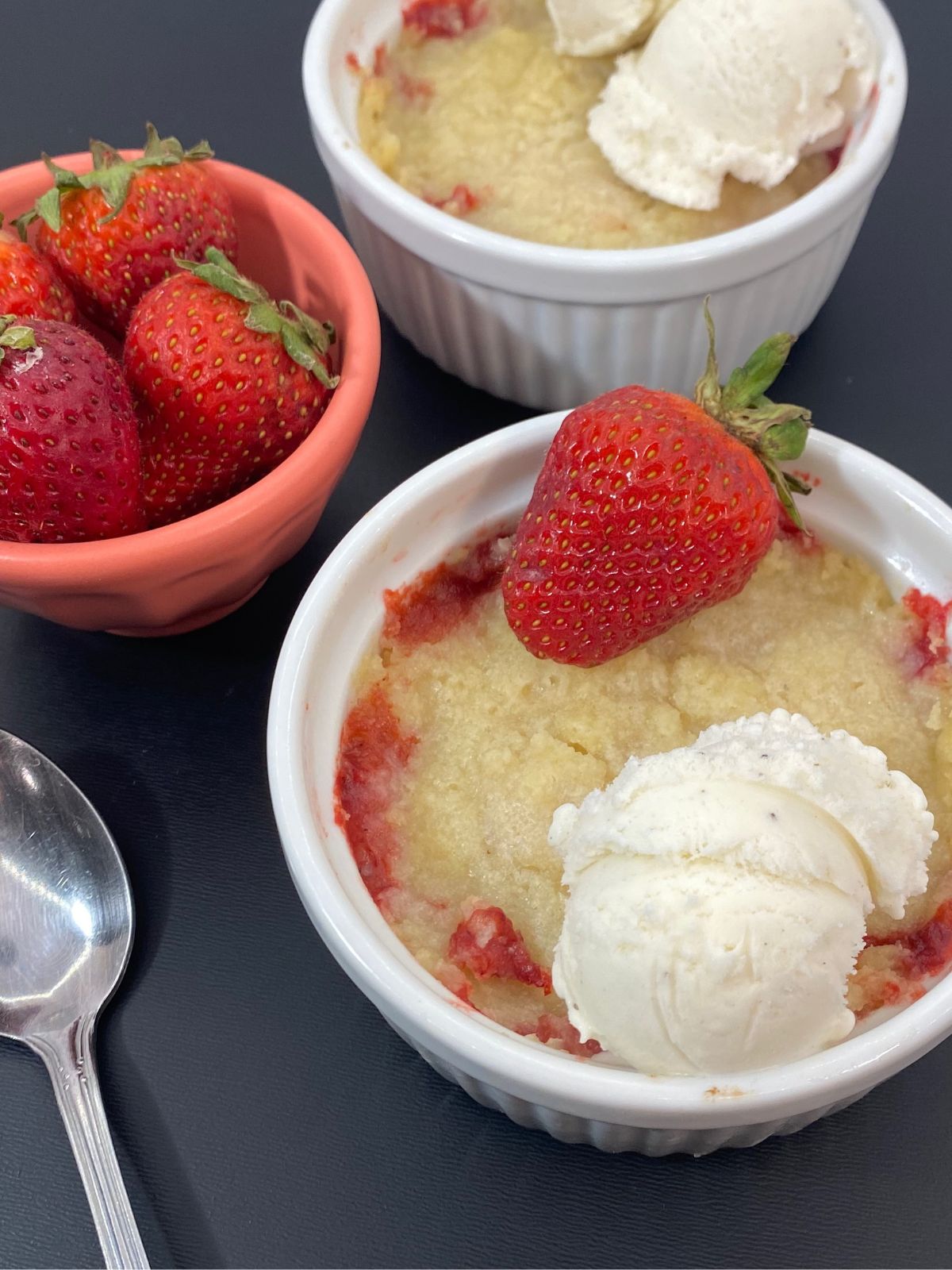 strawberry and apple crumble in ramekins topped with vanilla ice cream